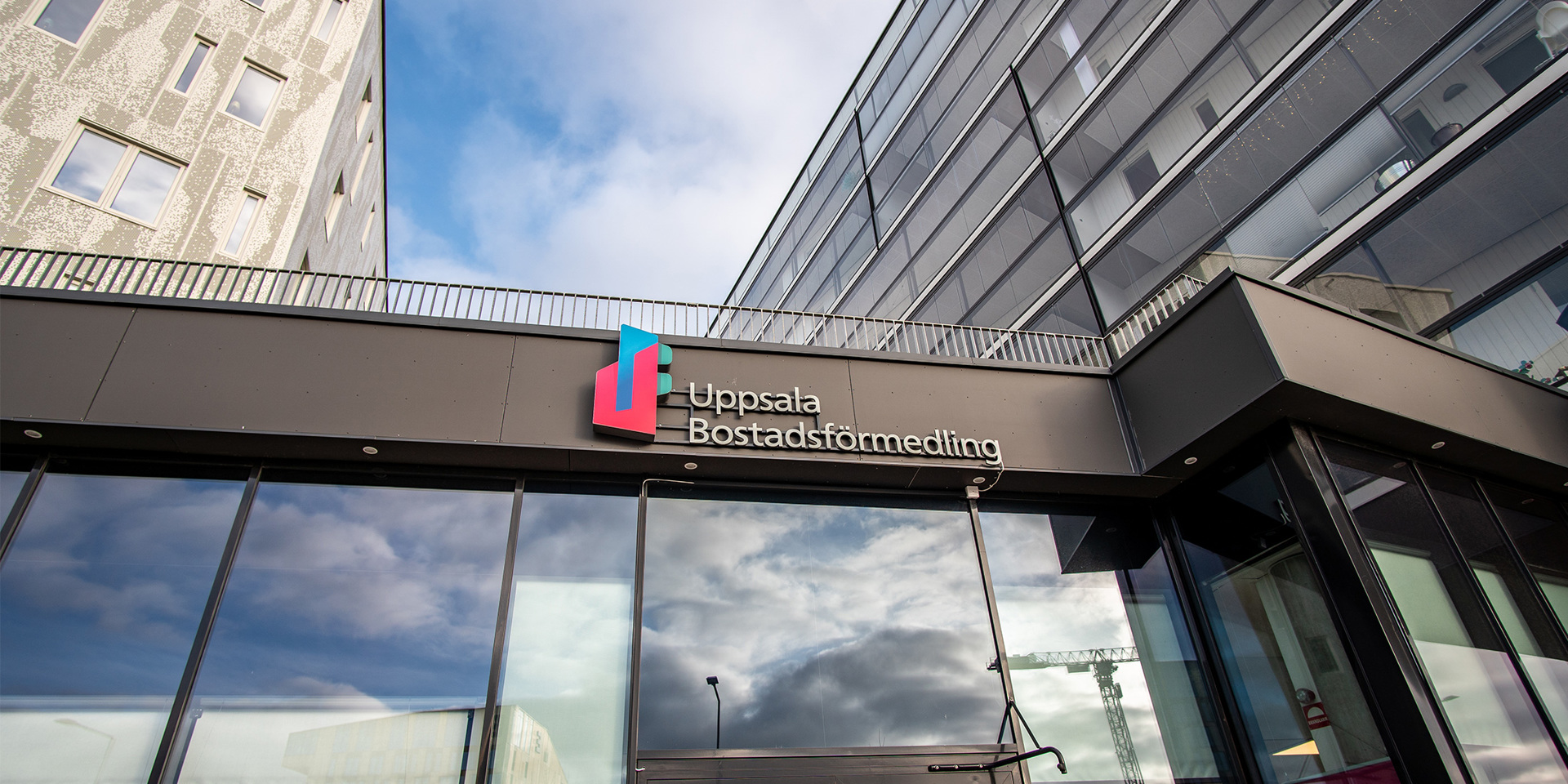Entré till Uppsala Bostadsförmedling med logotyp på glasfasad.